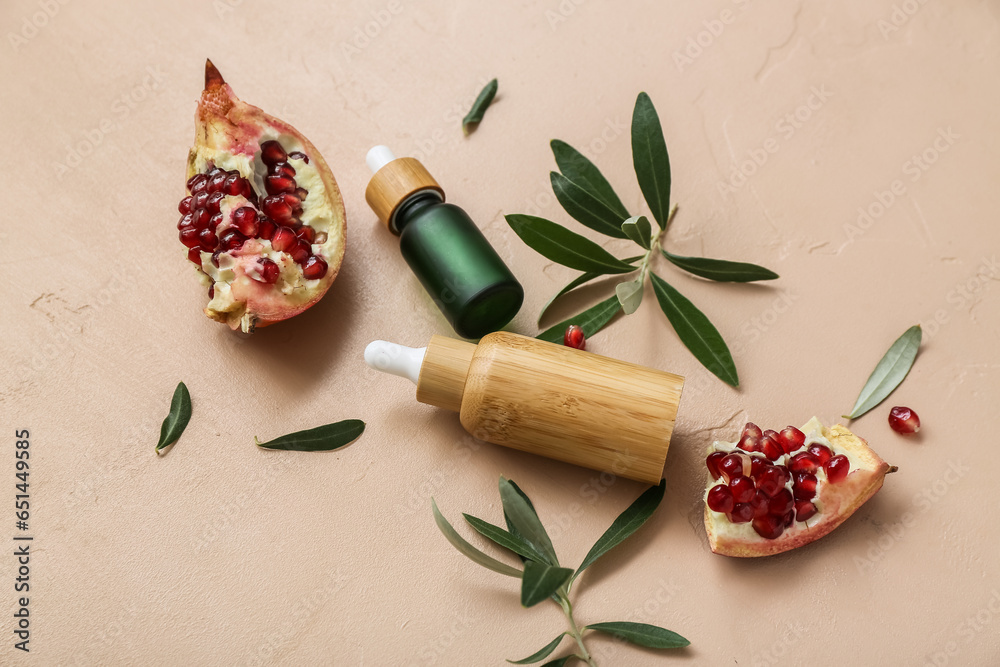 Composition with bottles of essential oil, pomegranate and plant branches on color background Composition with bottles of essential oil, pomegranate and plant branches on color background