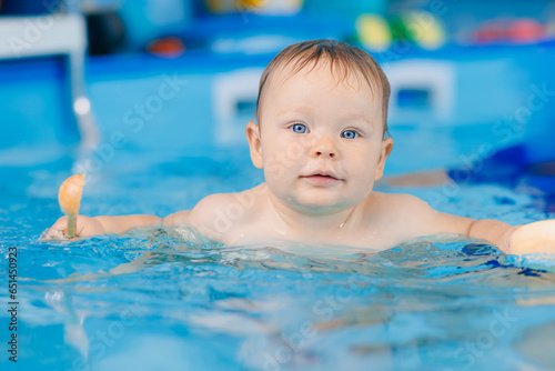 Portrait happy baby girl in swimming pool  teaching small swimmer. Concept healthcare sport for infant