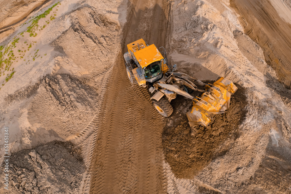 Yellow Industrial excavator working on sand quarry. Aerial top view open pit mine industry concept