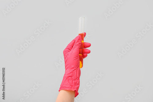 Lab's worker hand with test tube of sample on grey background