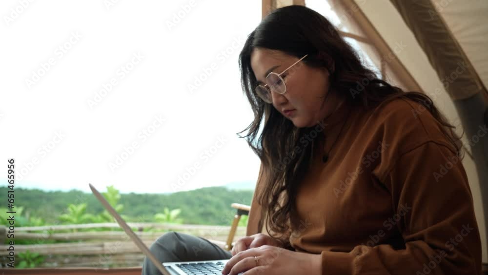 Asian woman digital nomad freelancer work typing on laptop while travelling camping.