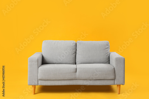 Cozy grey sofa on yellow background