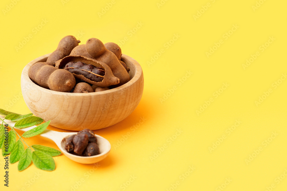 Fototapeta premium Bowl and spoon of tasty tamarinds on yellow background