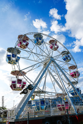 Ferris wheel against a blue sky with white clouds. Amusement park. © Elly Miller