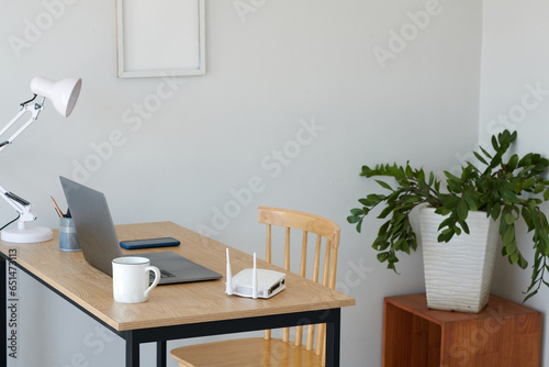 Desk with laptop, cup of coffee and Wi-Fi router in home office © DragonImages
