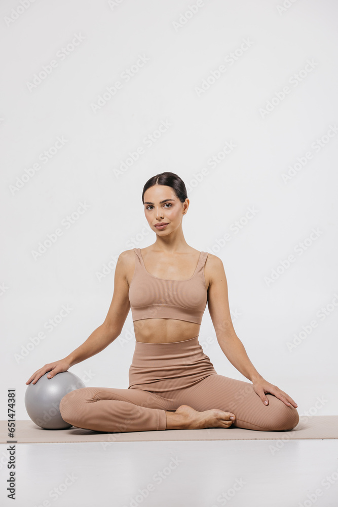 A beautiful young woman with a slim figure does sports exercises isolated on a light background. Self-love. The concept of beauty, style, fashion, cosmetology, body and skin care, sports, advertising.