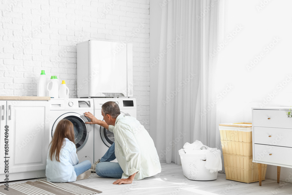Mature man with his little granddaughter doing laundry at home - obrazy, fototapety, plakaty 