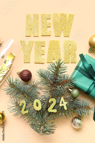 Fir branches with gift box  Christmas balls and text NEW YEAR 2024 on beige background