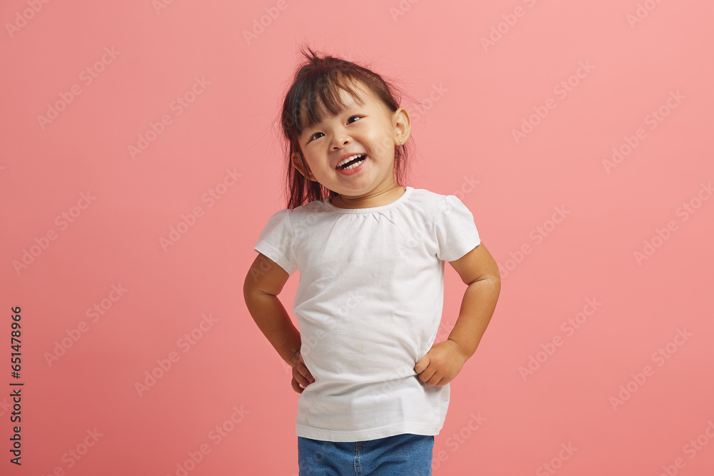 Cheerful three year old Asian girl smiles standing on pink isolated background. Beautiful Korean female child expresses a joyful mood on an isolated. Cheerful three year old Asian girl smiles standing on pink isolated background. Beautiful Korean female child expresses a joyful mood on an isolated.