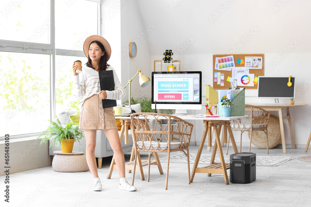 Asian interior designer with graphic tablet and cup of coffee in office Asian interior designer with graphic tablet and cup of coffee in office