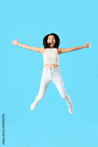 Jumping Asian woman on blue background © Pixel-Shot