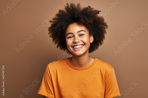 portrait beautiful afro american teenager girl dressed in t-shirt and smiling, light background