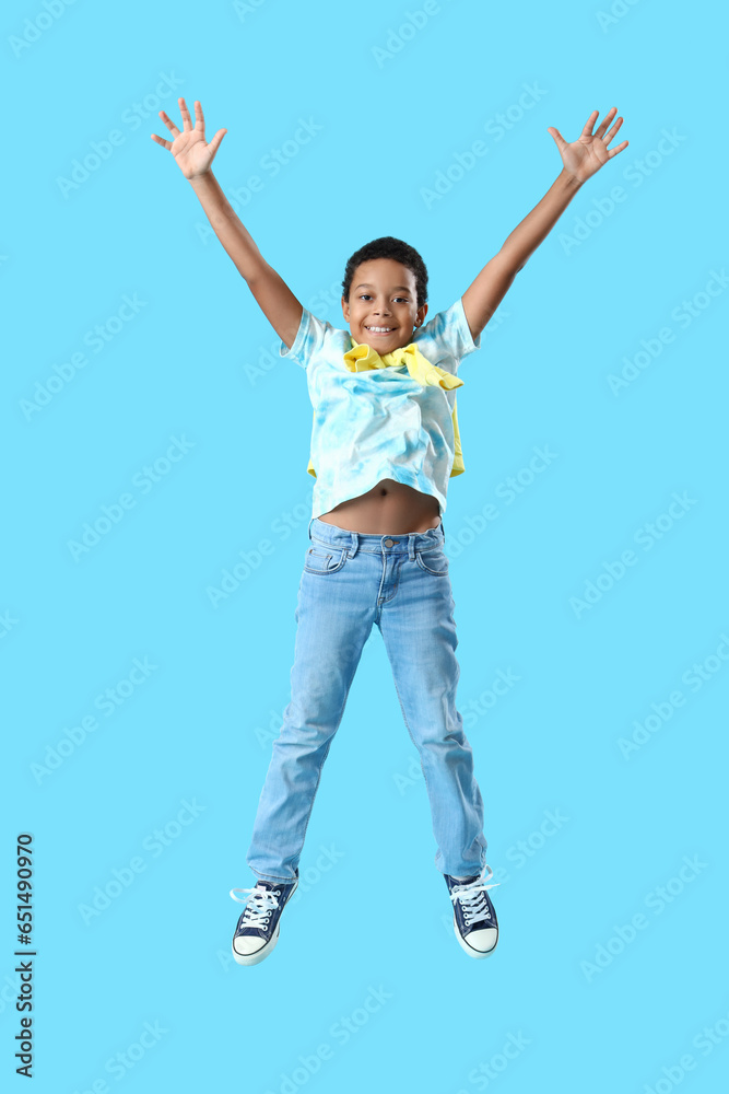 African-American little boy jumping on blue background African-American little boy jumping on blue background