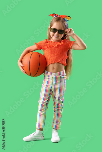 Cute little girl with ball on green background