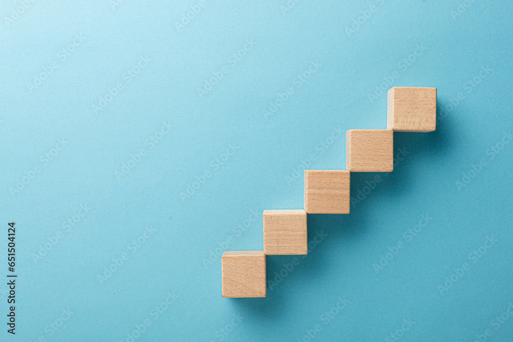 wooden cubes in the form of a ladder with a hand on a blue background