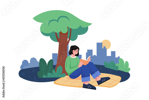 A little girl reading under a tree