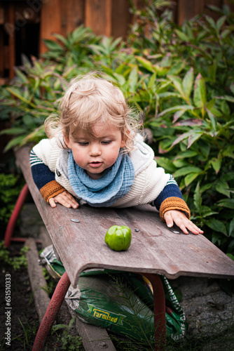 Baby schaut fragend auf eine grüne Paprika vor sich