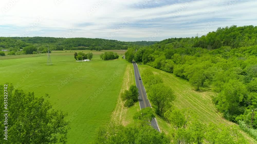 Aerial Descending Forward Shot Of Vehicles Moving On Road Near Green Trees Against Cloudy Sky - Crawfordsville, Indiana