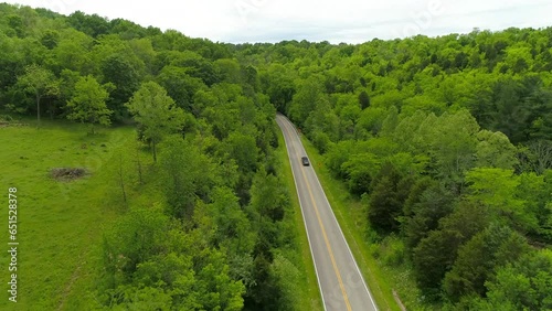 Aerial Forward Shot Of Vehicles Moving On Road Amidst Green Trees And Plants Against Sky - Crawfordsville, Indiana photo