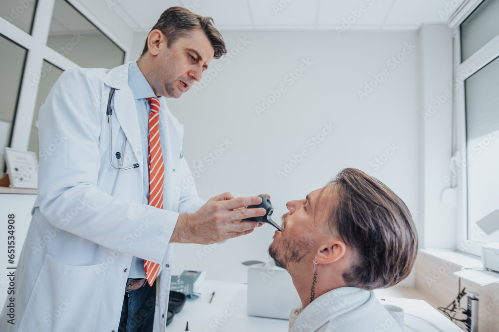 Fototapeta premium Experienced Doctor Examining Elderly Patient's Ears, Eyesight, and Throat in Clinic