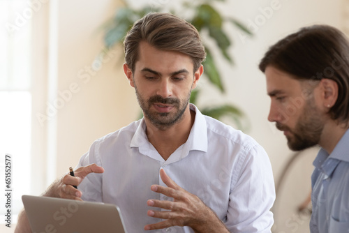 European workmates discuss project, confident executive manager makes presentation for client using notebook describe important moments convincing customer sign contract. Teamwork or mentoring concept photo