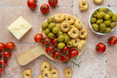 Cherry tomatoes, olives and tarallini on beige tiled background, top view photo