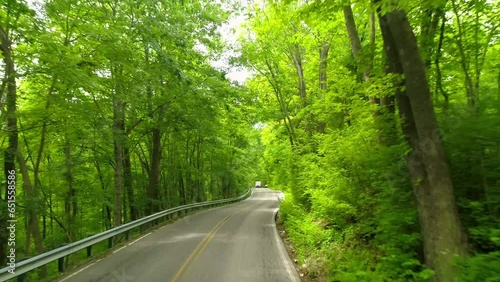 Aerial: Drone Flying Forward Over Vehicles Moving On Road Amidst Green Trees And Plants - Crawfordsville, Indiana photo