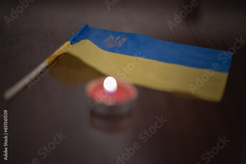 Burning candle and flag of Ukraine. Blackout due to the war in Ukraine