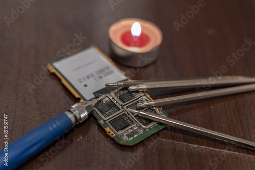 Burning candle and mobile phone motherboard for repair. Blackout due to the war in Ukraine