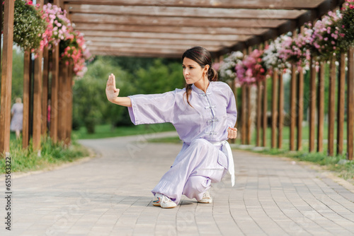 Bild auf Leinwand Portrait of serious woman wearing kimono training, practicing wushu in park