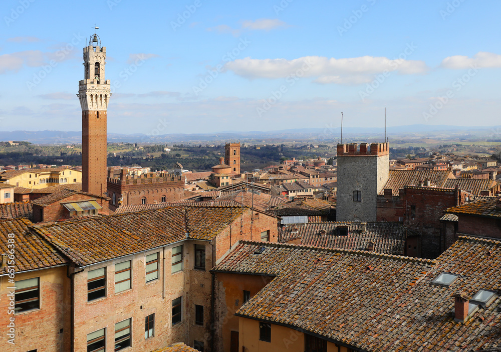 views of the tower called Torre del Mangia in the city of Siena and the terracotta tile roofs