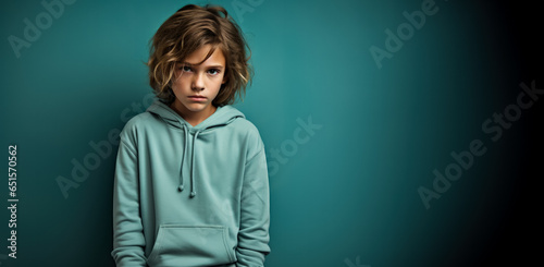 A shy child looking down isolated on a cool-toned gradient background 