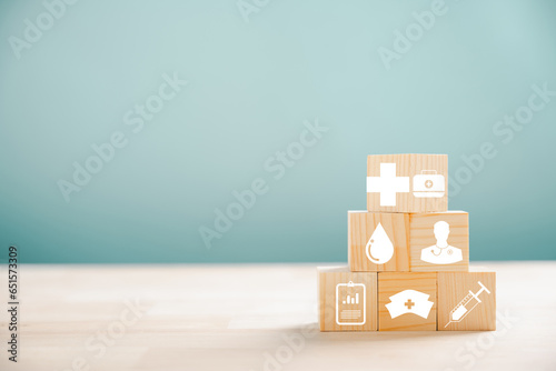 Healthcare and insurance illustrated by a pyramid of wooden cubes. Atop, a medical insurance icon on white background, leaving room for Health Insurance message.