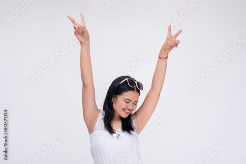 A lively party girl raising her arms in glee making victory signs. Isolated on a white background. photo