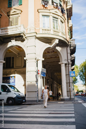 A young girl with long blonde hair in a white top and trousers on a city street in Europe