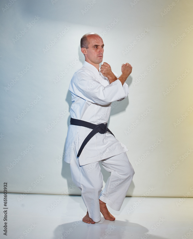Athlete with black belt training formal exercises on white background Athlete with black belt training formal exercises on white background