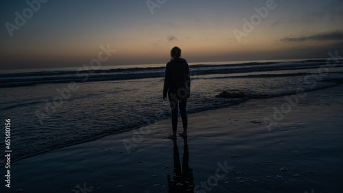 silhouette of a woman standing sunset on the beach