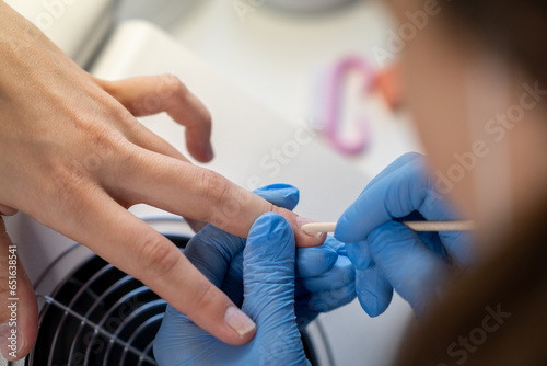 Nail care procedure in a beauty salon. Female hands and tools for manicure  process of performing manicure in beauty salon. Concept spa body care. Gloved hands of a skilled manicurist cutting cuticles
