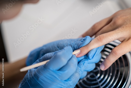 Nail care procedure in a beauty salon. Female hands and tools for manicure, process of performing manicure in beauty salon. Concept spa body care. Gloved hands of a skilled manicurist cutting cuticles