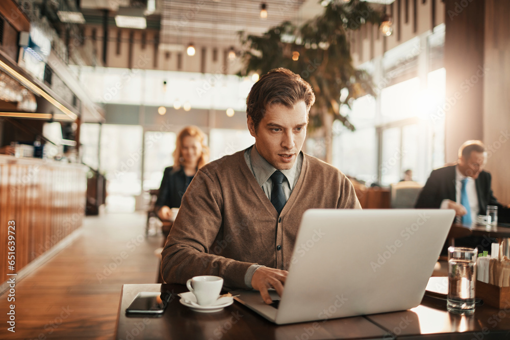 Young businessman using a laptop in a cafe decorated for christmas and the new year holidays Young businessman using a laptop in a cafe decorated for christmas and the new year holidays