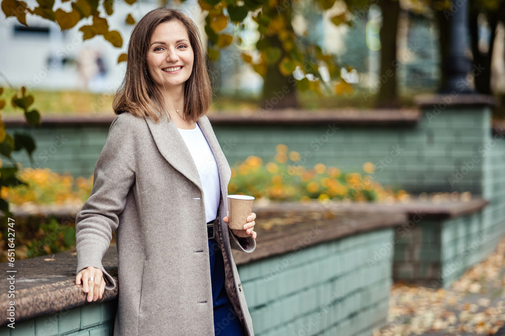 A young woman on a walk in an autumn park, holding a glass of coffee in her hands. Copy space A young woman on a walk in an autumn park, holding a glass of coffee in her hands. Copy space