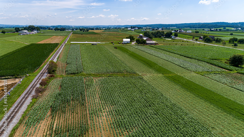An Aerial View of Amish Farmlands with Corn Growing and Harvesting Alfalfa, by a Single Railroad Track, on a Sunny Summer Day