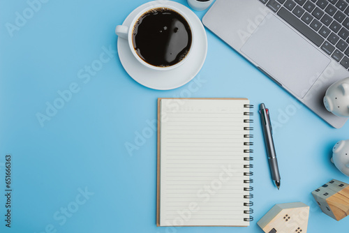 Top view, Save money investment estate. Flat lay a laptop, coffee of a white cup, with two piggybanks on blue background with copy space. Investment, Accounting, Financial concept.