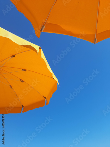 Yellow beach umbrellas isolated on blue sky background.