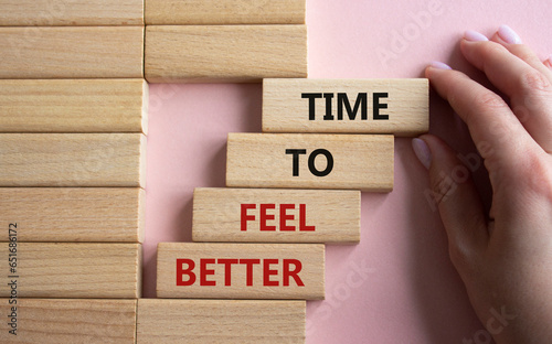 Time to feel better symbol. Wooden blocks with words Time to feel better. Businessman hand. Beautiful pink background. Medicine and Time to feel better concept. Copy space.