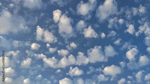 Landscape with altocumulus clouds moving across the blue sky in the afternoon