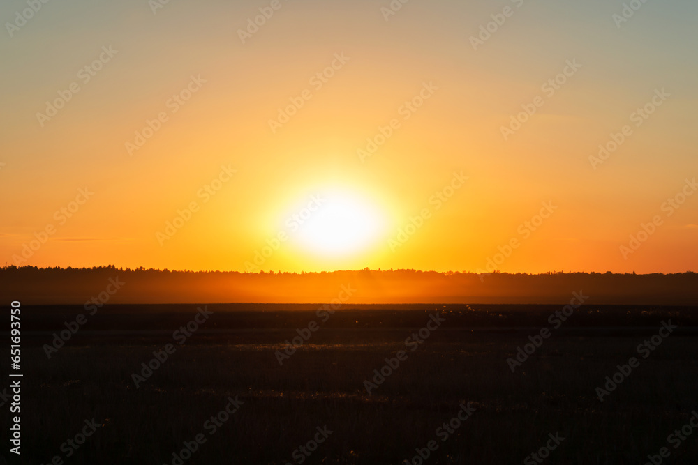 Sunset above forest and agricultural field in autumn time, yellow orange color sunset, low key photo
