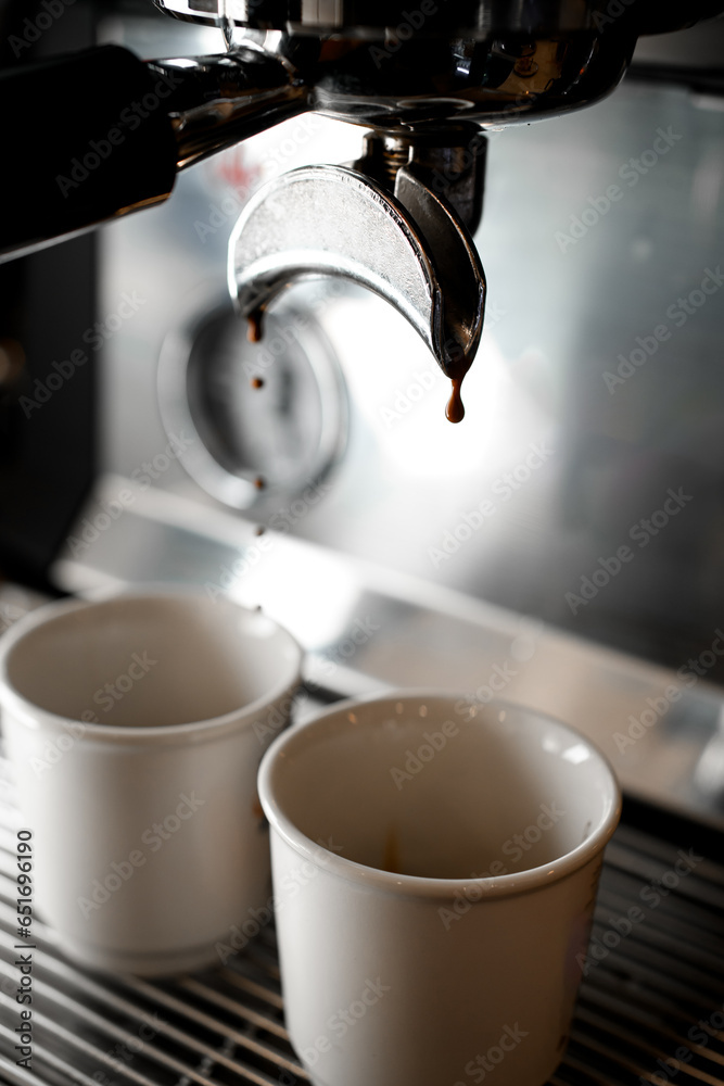 Macro shot of drops of strong coffee pours in small white cups Macro shot of drops of strong coffee pours in small white cups