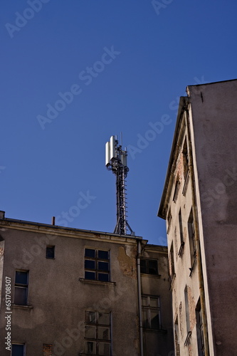 Fasada starej zniszczonej kamienicy w mieście, narożnik, na dachu antena, słoneczny dzień