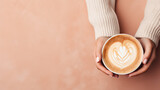Top view of a female hands in a warm sweater holding mug of delicious cappuccino coffee. Pastel pink background with copy space, banner template. 